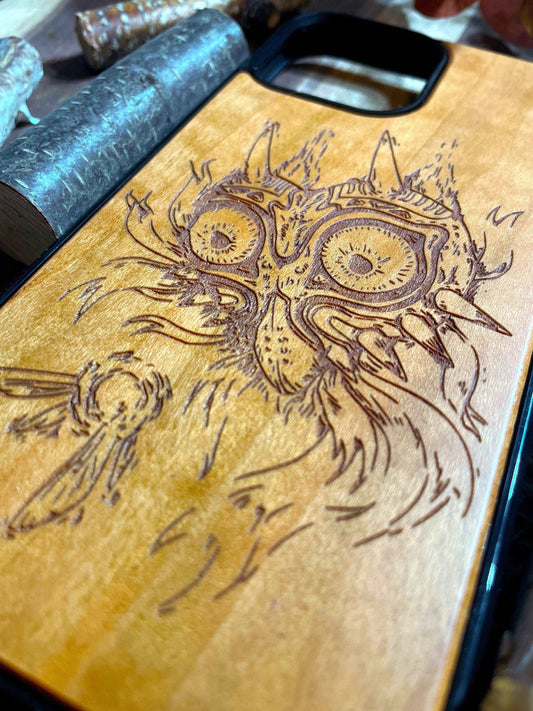 a wood phone case with a picture of a zelda majoras mask on it